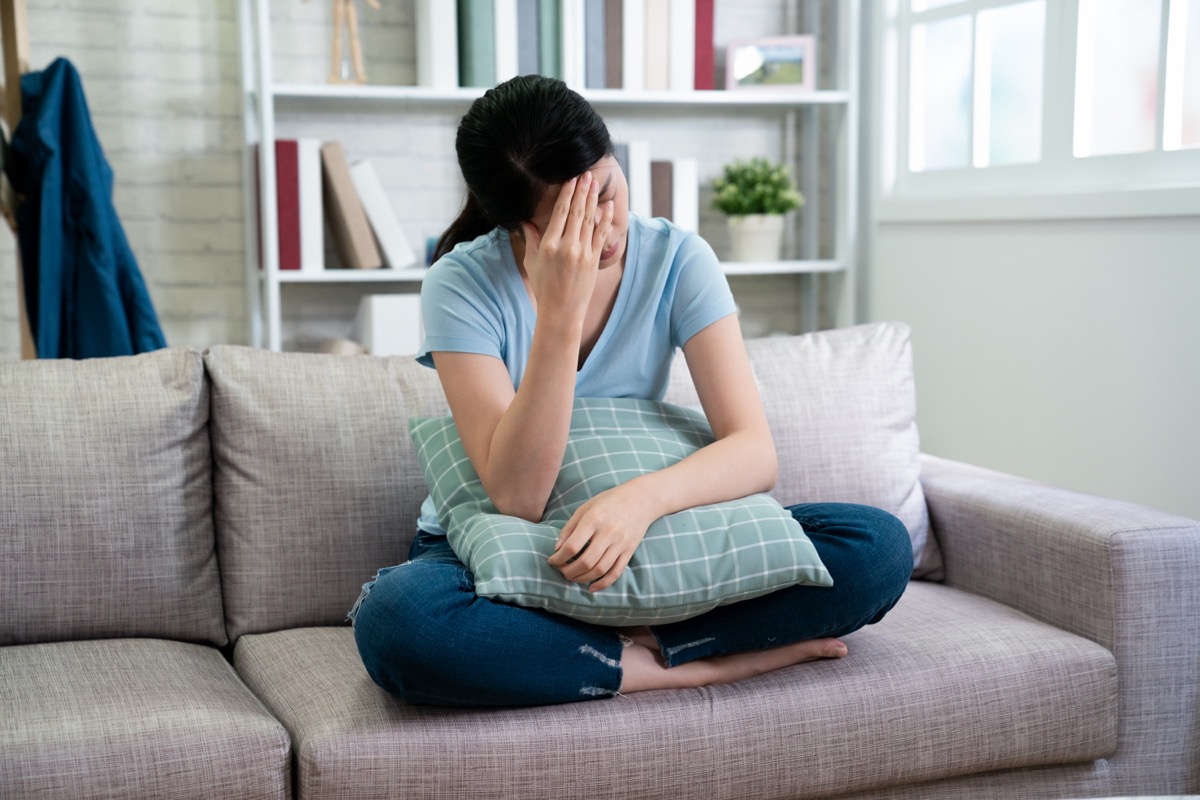 Asian woman sitting on the couch feeling sad and depressed
