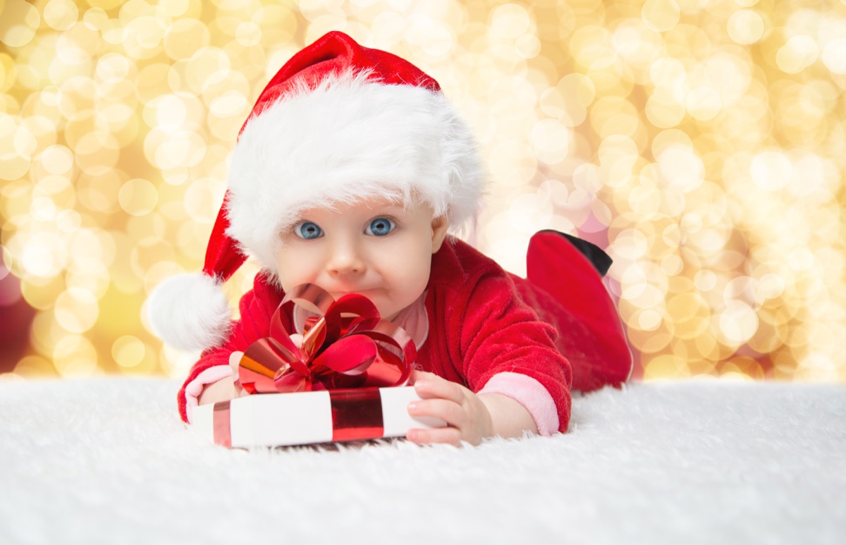 baby in a christmas onesie holding a gift