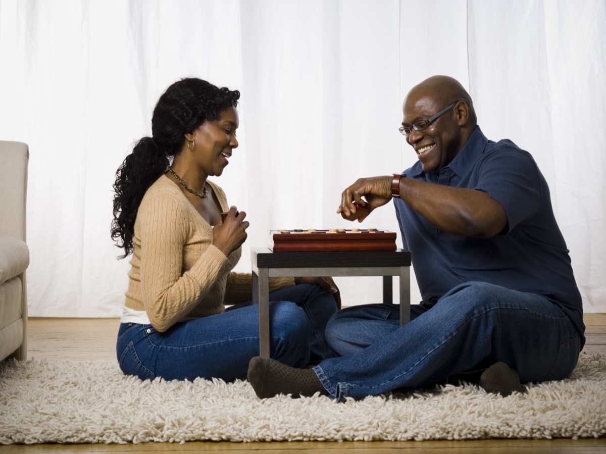 middle aged black couple playing board game on floor