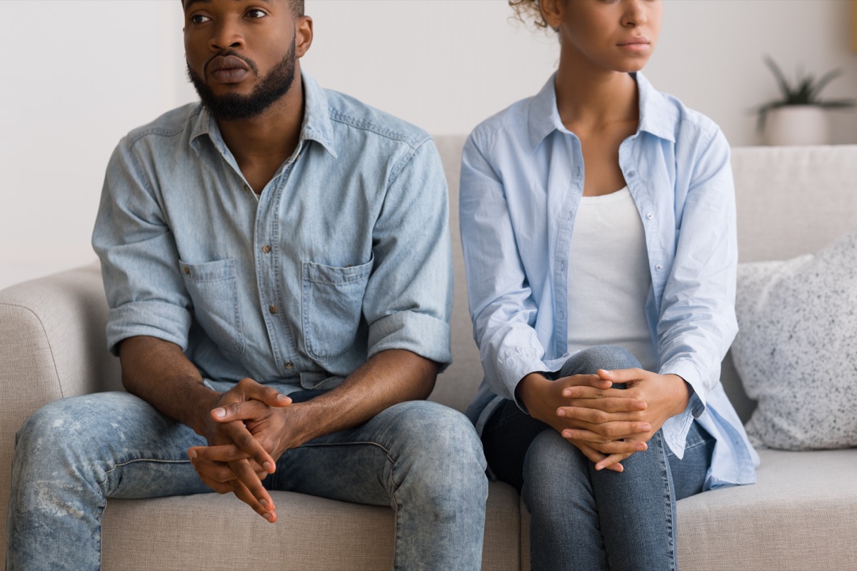 young black woman and man sitting on couch looking upset