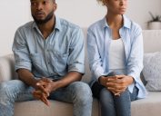 young black woman and man sitting on couch looking upset