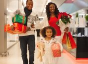 30-something black mother and father and young daughter shopping for holiday gifts at a department store or mall