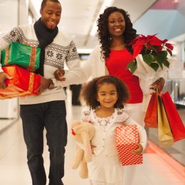 30-something black mother and father and young daughter shopping for holiday gifts at a department store or mall