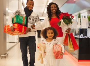 30-something black mother and father and young daughter shopping for holiday gifts at a department store or mall