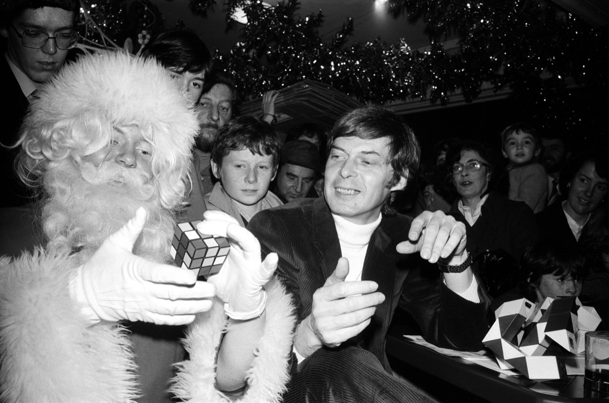 The Rubik cube's inventor Professor Erno Rubik in the toy department of Harrods, autographing his cubes and new toy the Snake. He even found time to demonstrate the cube to Santa who happened to be in the store at the same time. London, 7th December 1981.