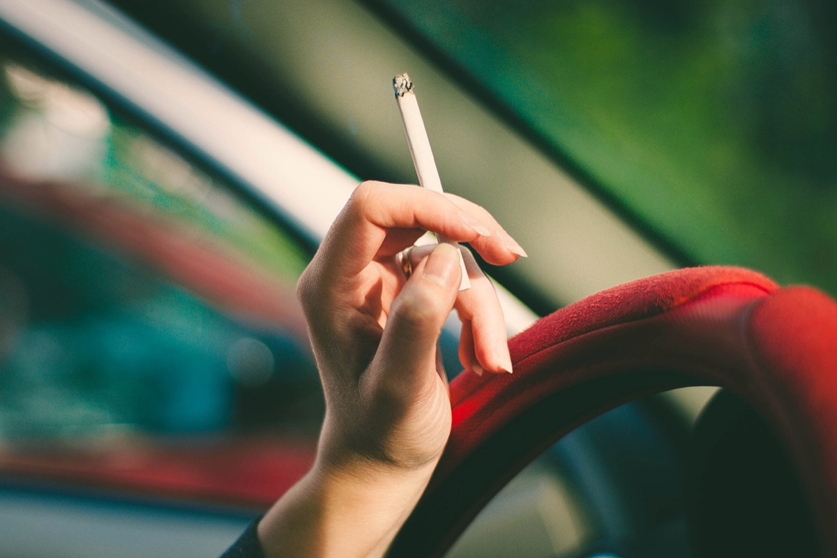 Woman in a car with a cigarette in her hand