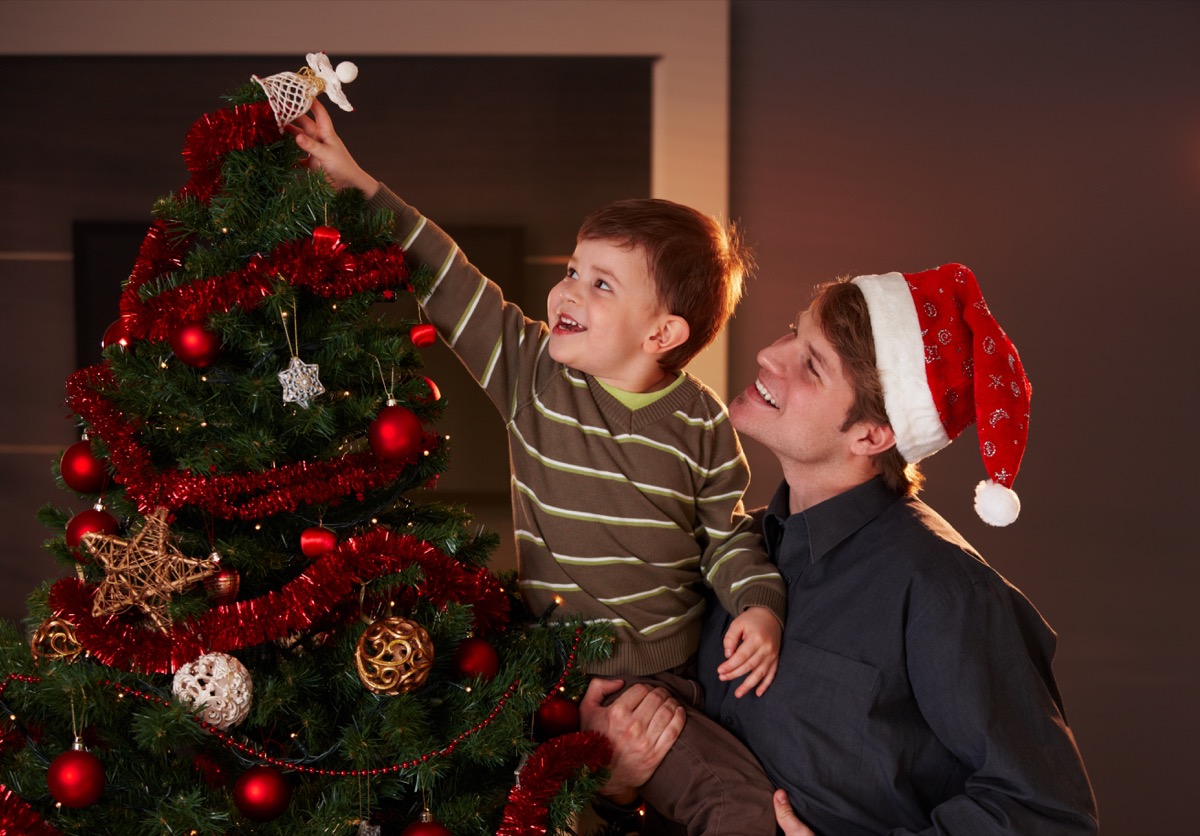 dad helping son decorate a christmas tree