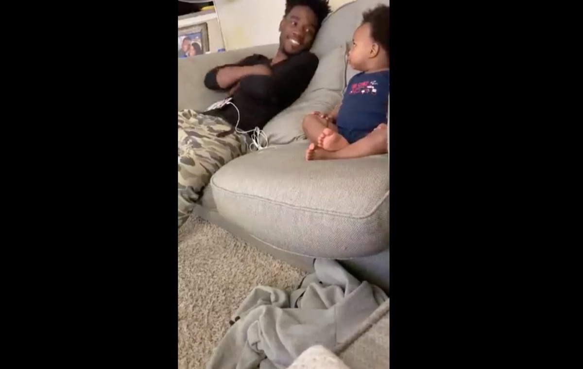 young black father having conversation with toddler son on couch