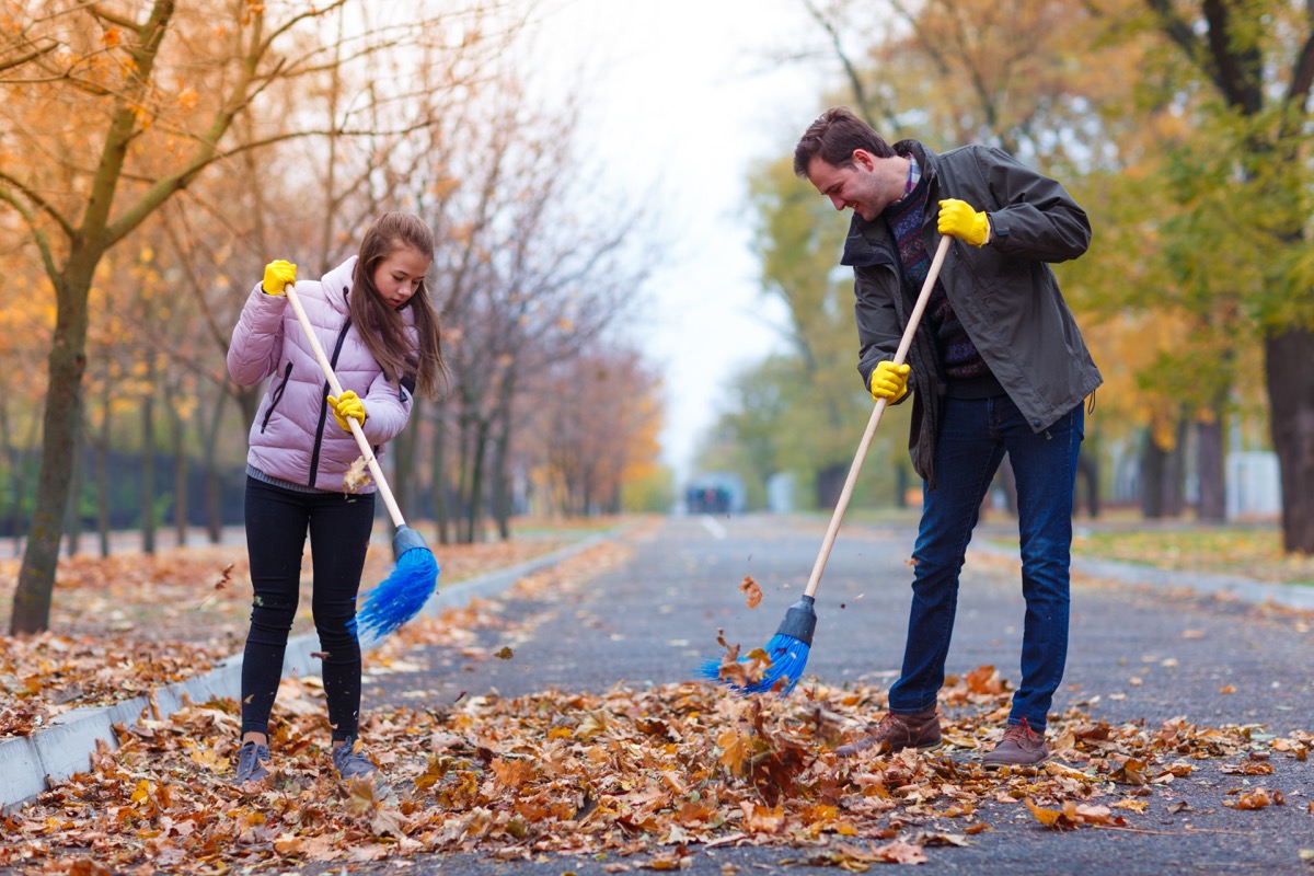 white dad and daughter raking leaves