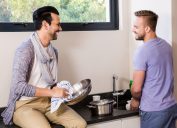 Gay couple washing dishes and smiling