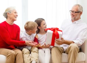 white grandparents getting gifts from their two grandkids on couch
