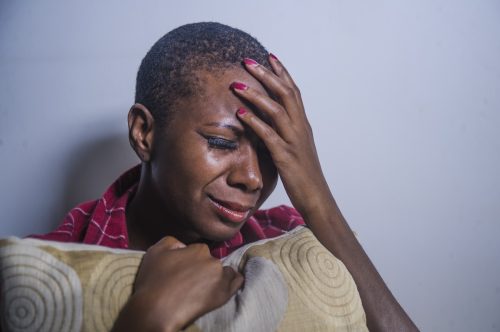 black woman crying and clutching a pillow