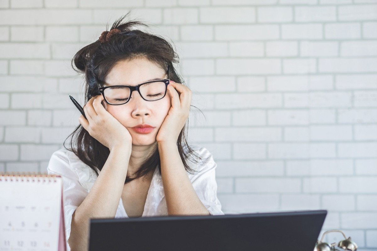 young asian woman falling asleep at her desk