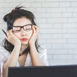 young asian woman falling asleep at her desk