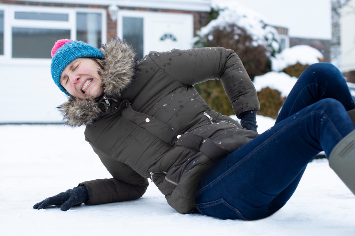 white woman who has fallen on snow grimacing in pain