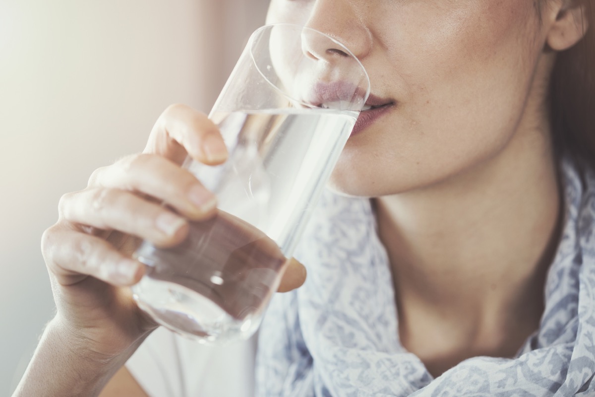 close up of young woman drinking a glass of water