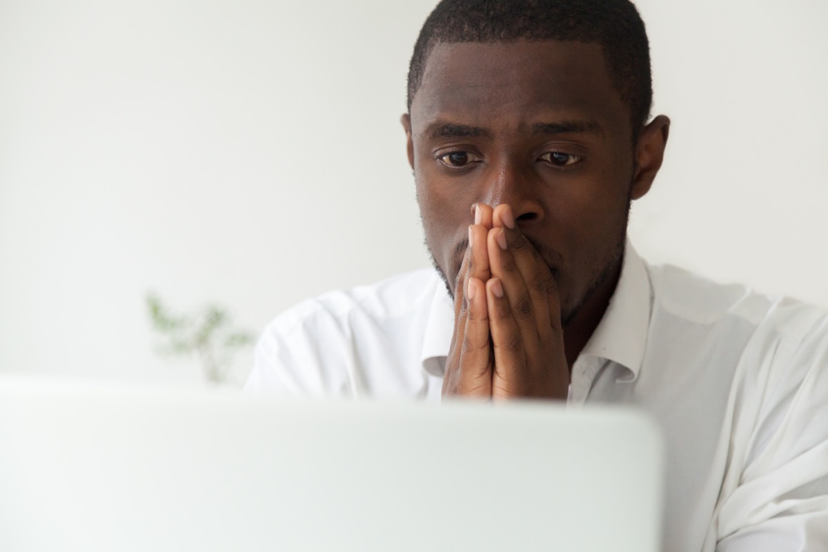 Black man sitting by his computer feeling stressed and anxious
