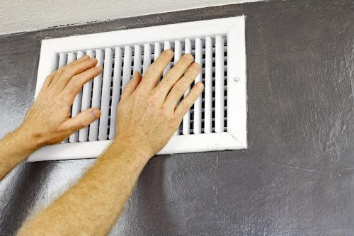 white man opening heating vent