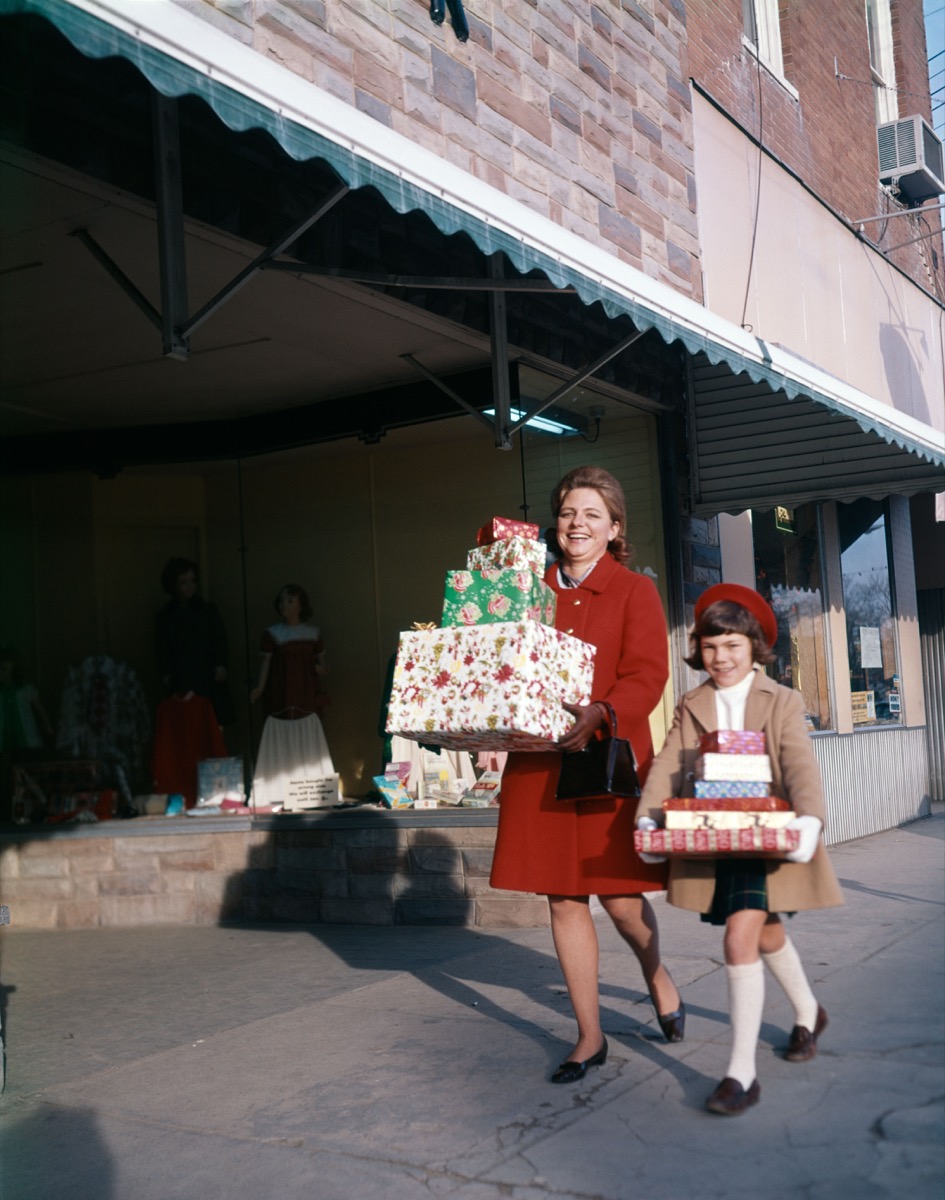 1970 1970s MOTHER DAUGHTER CARRYING STACKS OF GIFT PACKAGES MALL
