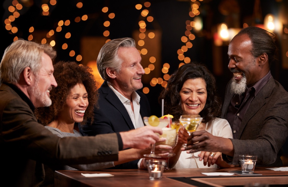 older guests of all ethnicities gather at party, toasting glasses 