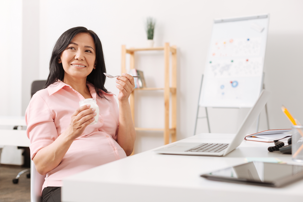 Pregnant asian woman eating yogurt