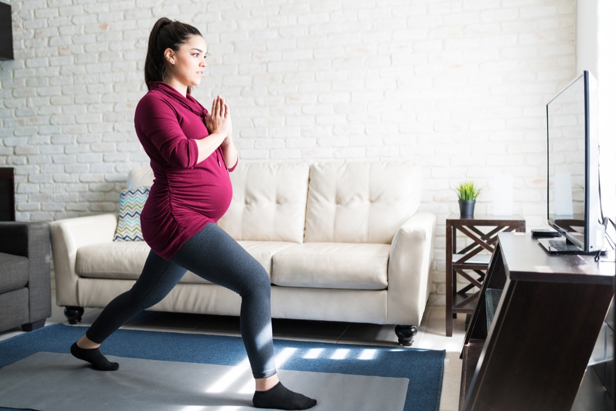 Pregnant woman doing lunges in her living room