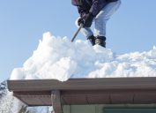 man scraping snow off roof
