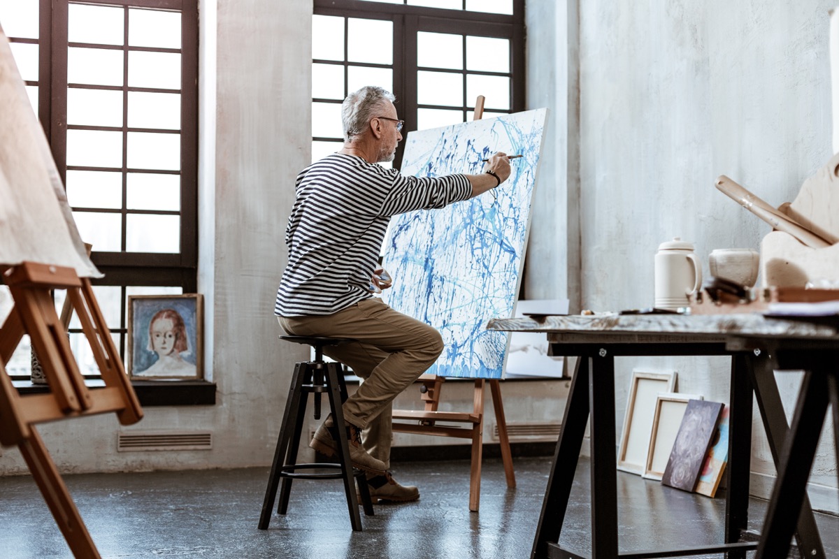 senior man painting on canvas