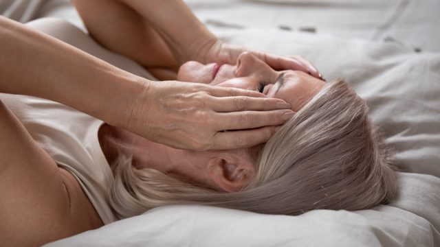 Stressed woman touching her face on the bed