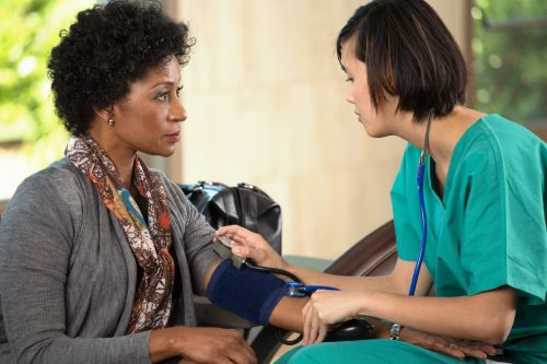 Kontrolle des Blutdrucks einer Frau in der Arztpraxis