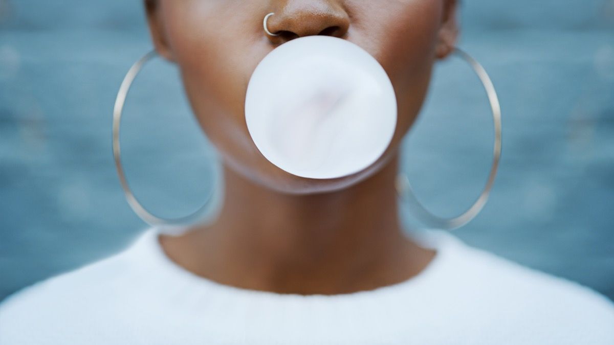 woman blowing a piece of gum and chewing it