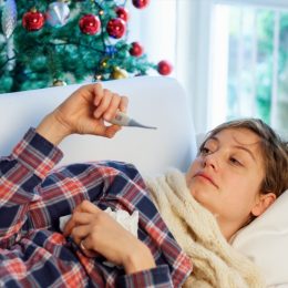 Woman sick on the couch on Christmas with a fever potentially from the flu