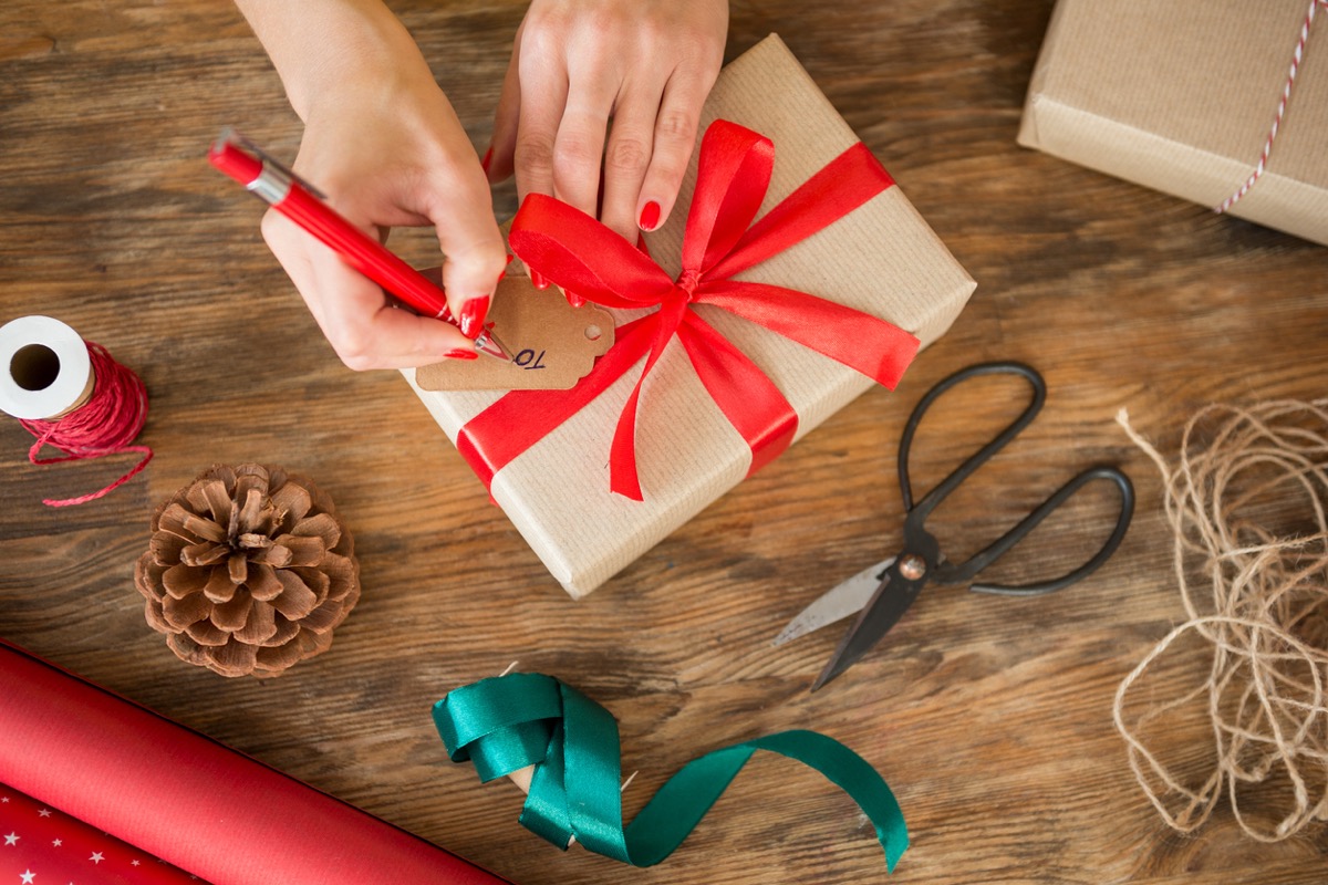 white woman filling out gift tag on christmas present