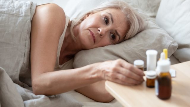 Woman sick in bed taking medication