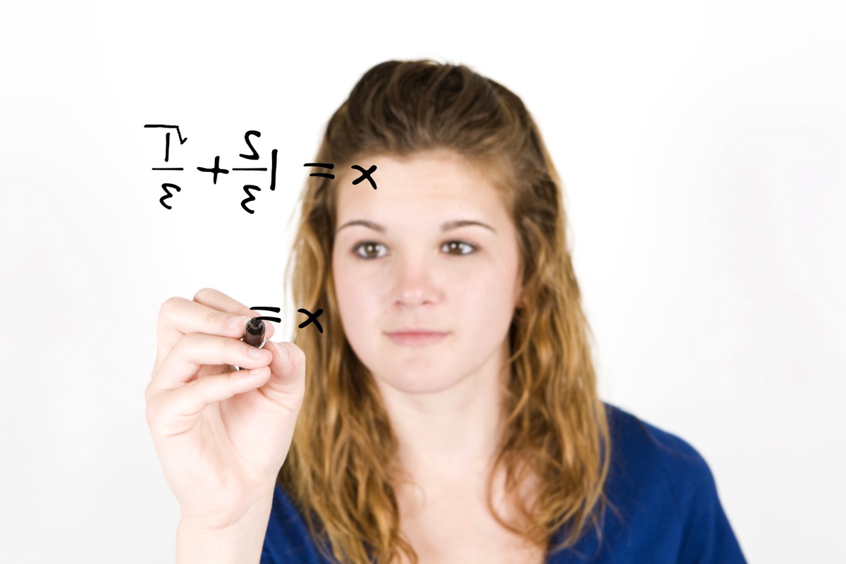 Older teenager solving fractions and doing math on a board