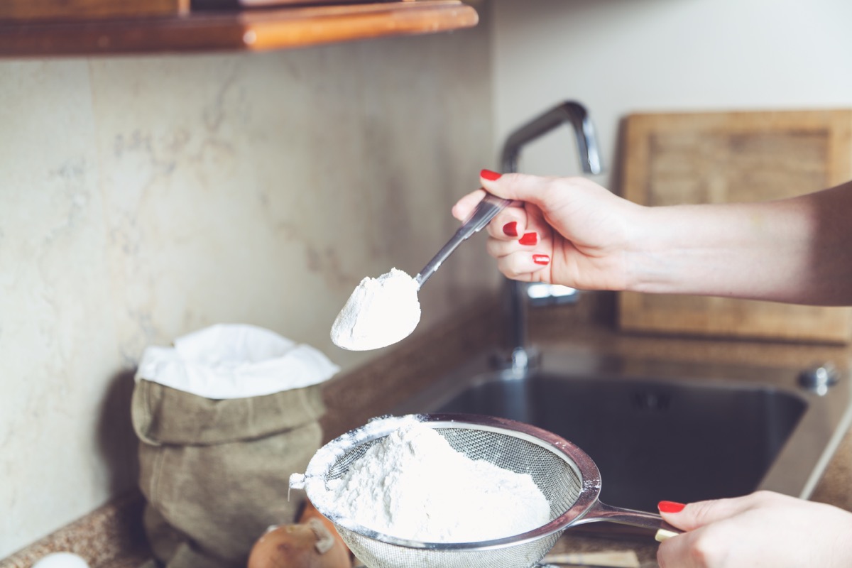 white woman spooning flour into sieve