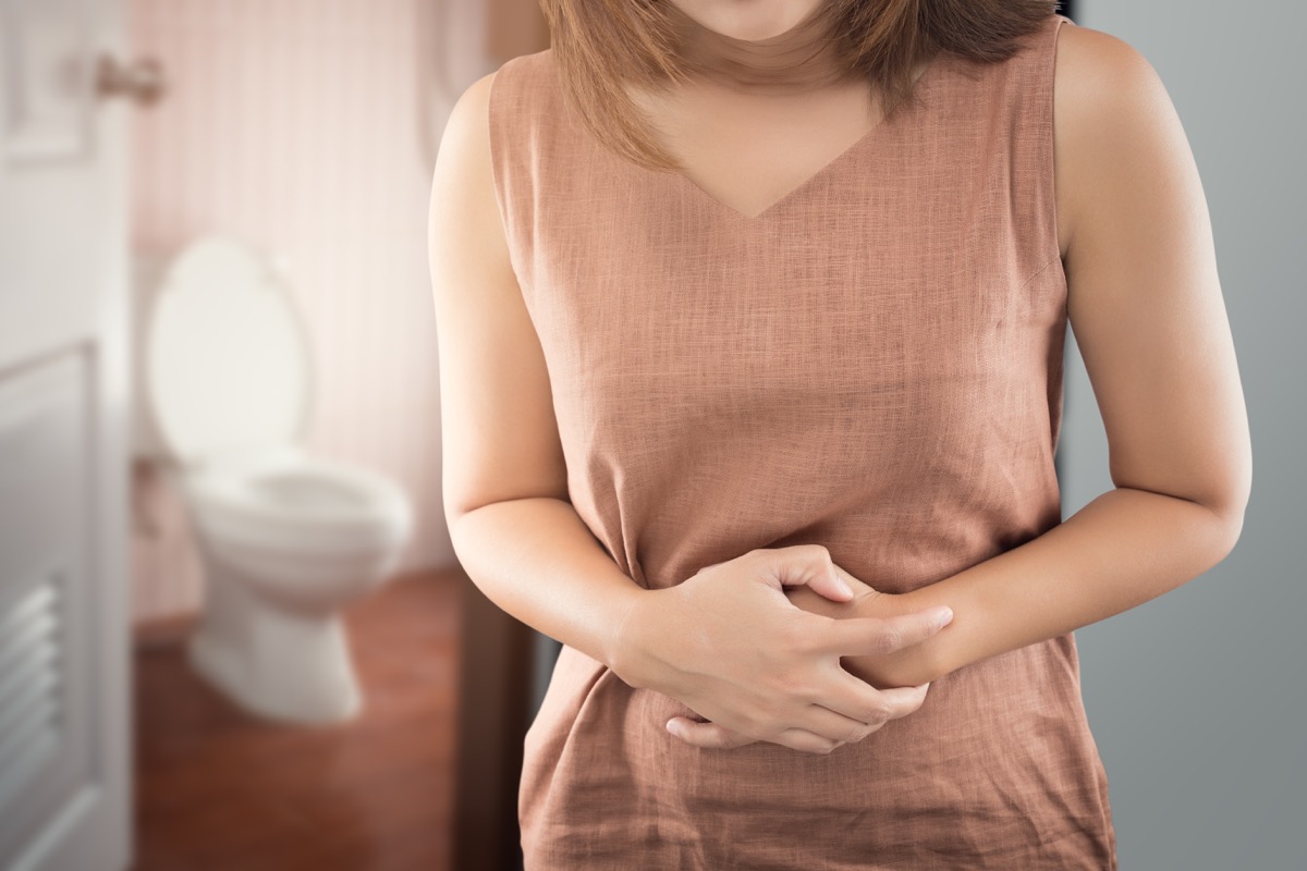 Woman holding her stomach in pain right outside the bathroom