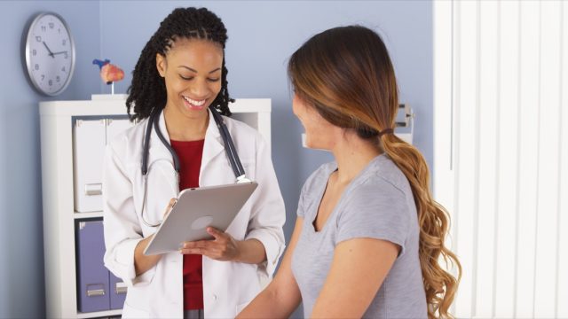 Black doctor talking to a woman and giving her a check-up