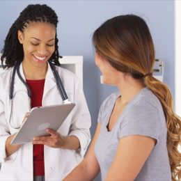 Black doctor talking to a woman and giving her a check-up