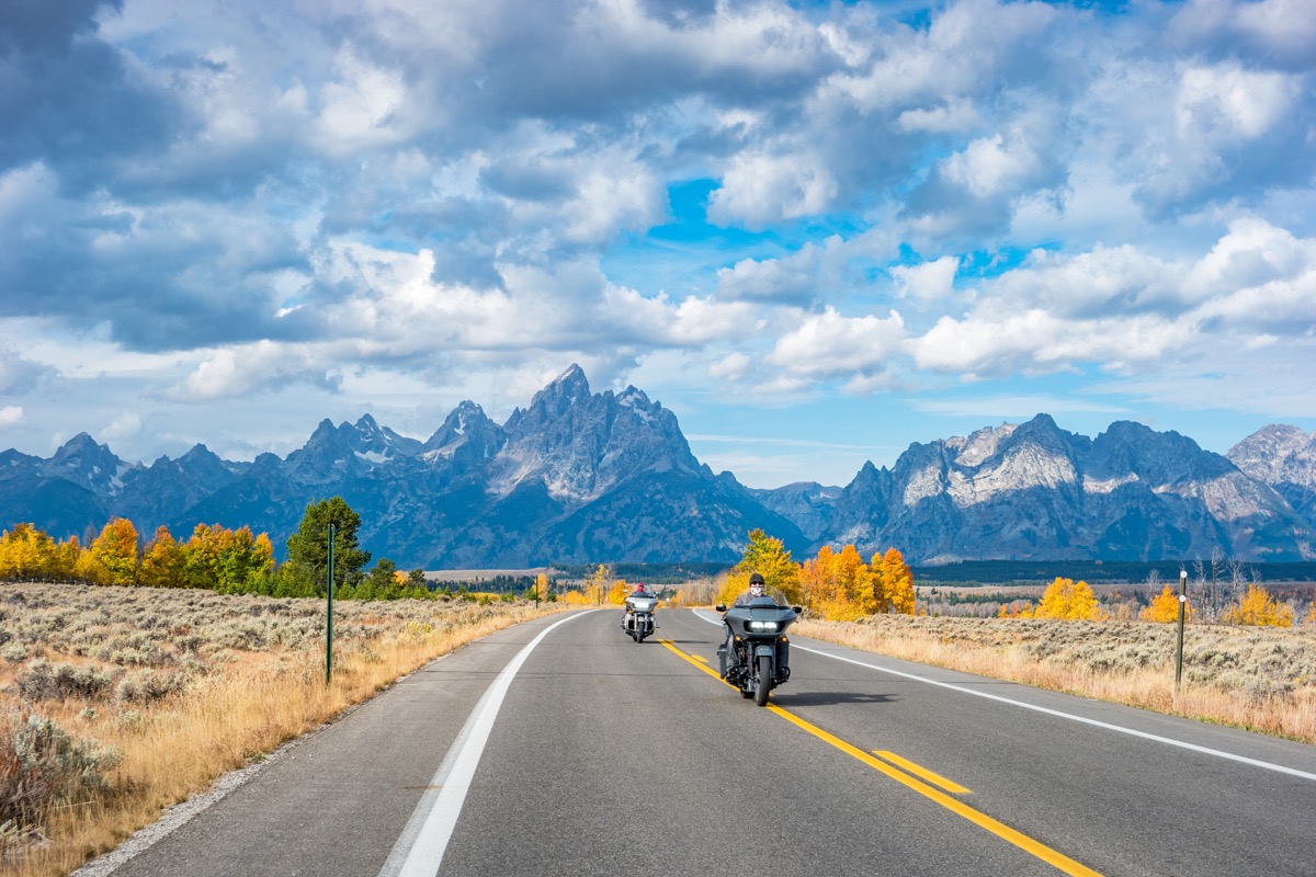 Bikers ride motorcycles in Grand Teton National Park, Wyoming, USA on a cloudy autumn day.