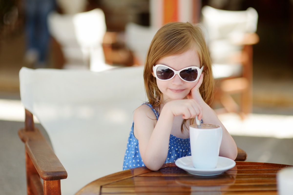 young white girl in sunglasses drinking coffee outside