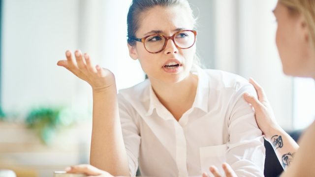 anxious woman explaining reason of her worry to friend by cup of coffee