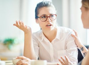 anxious woman explaining reason of her worry to friend by cup of coffee