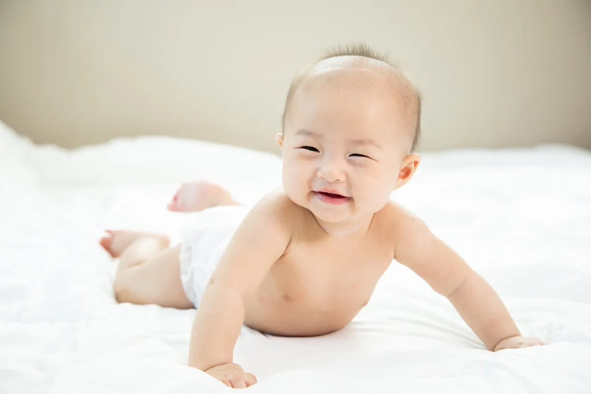 smiling asian baby doing tummy time