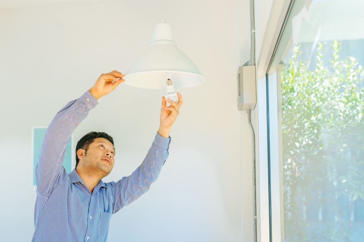 young asian man fixing light bulb