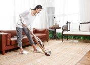 asian woman vacuuming area rug