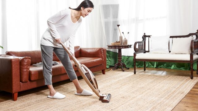 asian woman vacuuming area rug