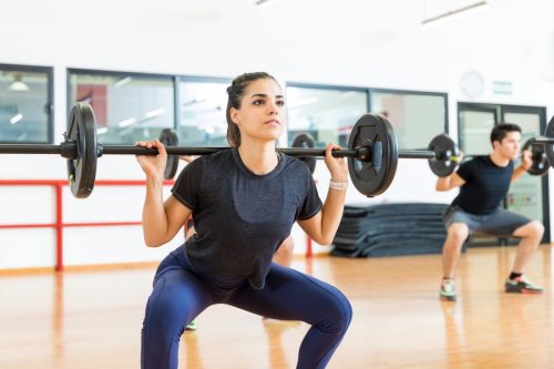 Woman doing a barbell squat in a workout class