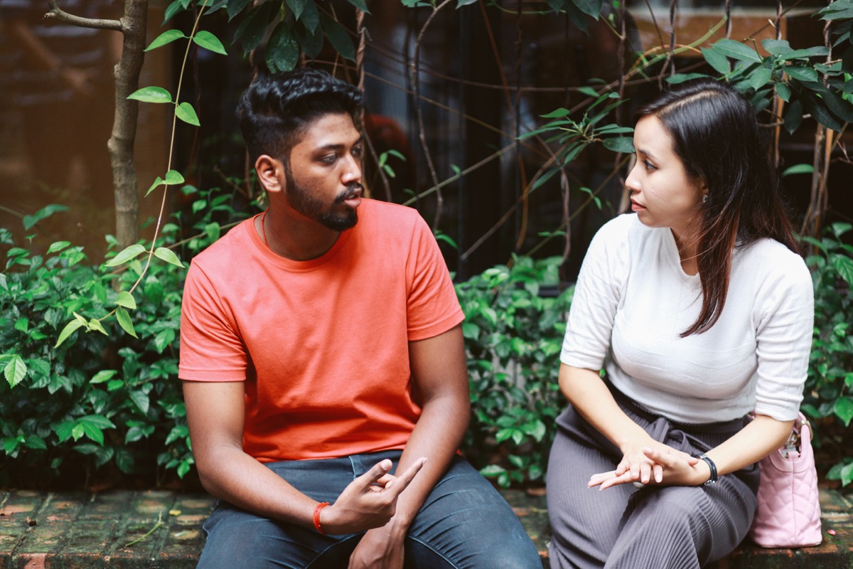 young people talking and flirting on the streets of Kuala Lumpur, having a coffee break together in front of their office or university library.