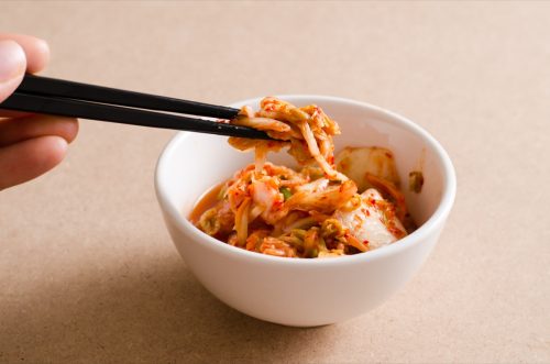 Person eating fermented kimchi with chopsticks